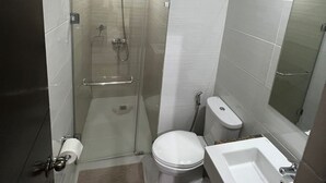 A compact bathroom with a glass-enclosed shower, a toilet, and a sink. - Chic 1-bedroom building in fantastic Pasay City with AC, fitness room (Pasay City)