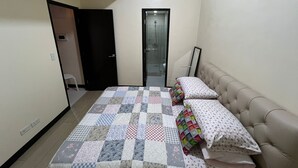 A bedroom with a bed, a bedside table, a mirror, and a door leading to a bathroom. - Chic 1-bedroom building in fantastic Pasay City with AC, fitness room (Pasay City)