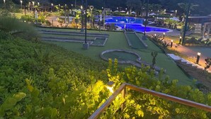 A landscaped pool area with a circular water feature, surrounded by well-maintained greenery and outdoor seating. - Family condo with resort-style pools, close to beaches, nature and adventure. (puntarenas)