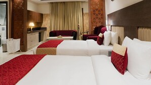 Habitación de hotel con dos camas, un escritorio, una silla y un armario.