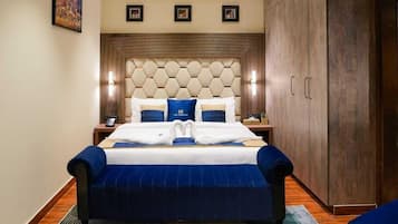 A hotel room with a large bed, wooden headboard, and a wardrobe.