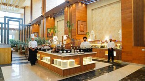 A buffet setup with chefs, a marble floor, wooden paneling, and a large window. - The Meriton (New Delhi)
