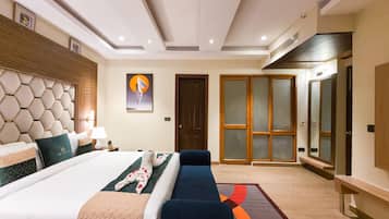 A hotel room with a large bed, a sofa, a desk, and a wardrobe.