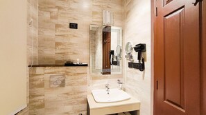 Un baño con pared de mármol, lavamanos, espejo, secador de pelo y toallero.