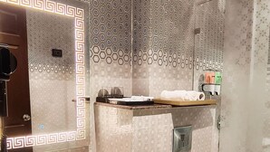 Un baño moderno con un espejo grande, un lavamanos, un inodoro y una ducha.