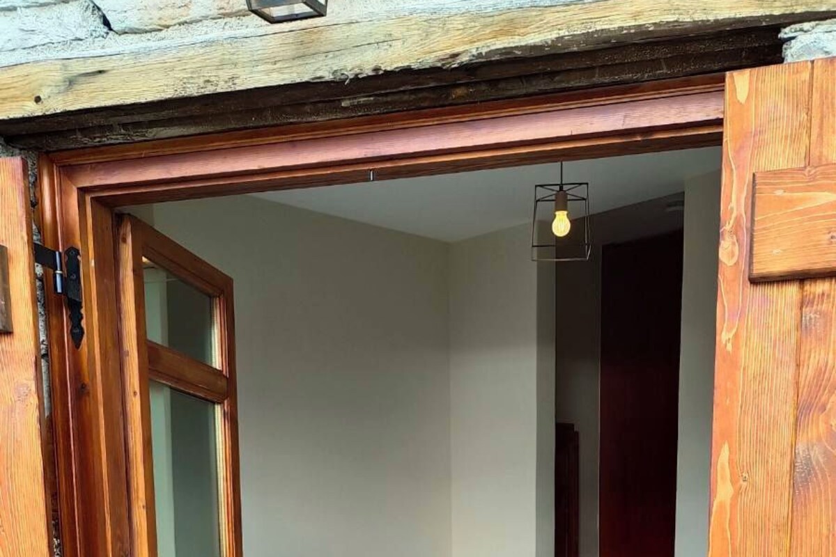 Una camera da letto con pavimento in pietra, un letto con lenzuola bianche e un comodino con una lampada.