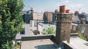 A rooftop terrace with a brick chimney, a small garden, and a view of neighboring buildings. - Fabian Road Cozy House - Central London (London)