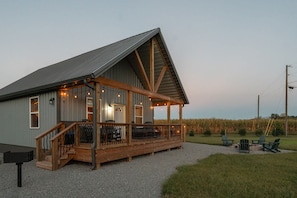 A rustic building with a covered porch, wooden railings, and outdoor seating.
