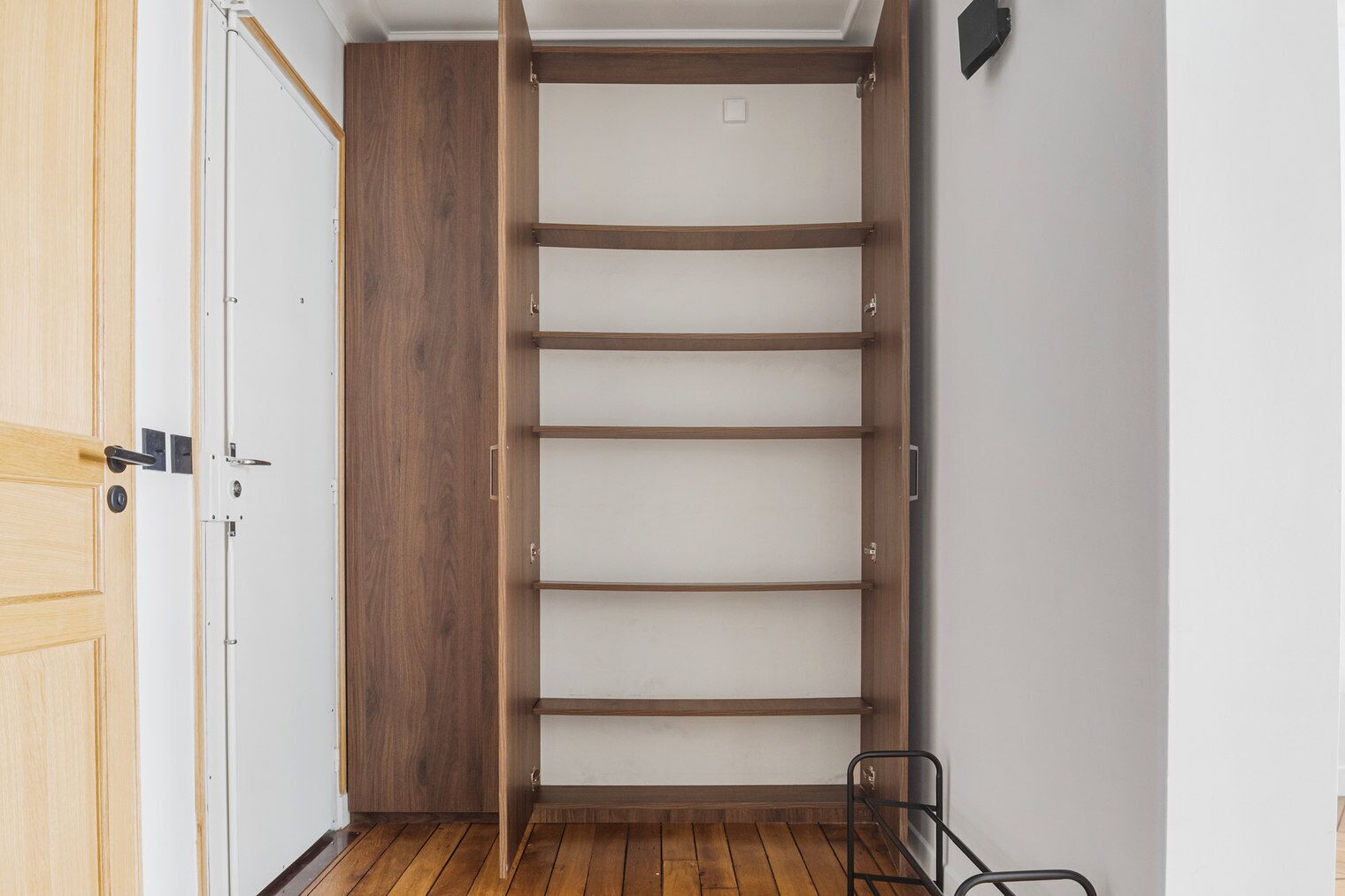 Een inloopkast met houten deuren en planken.