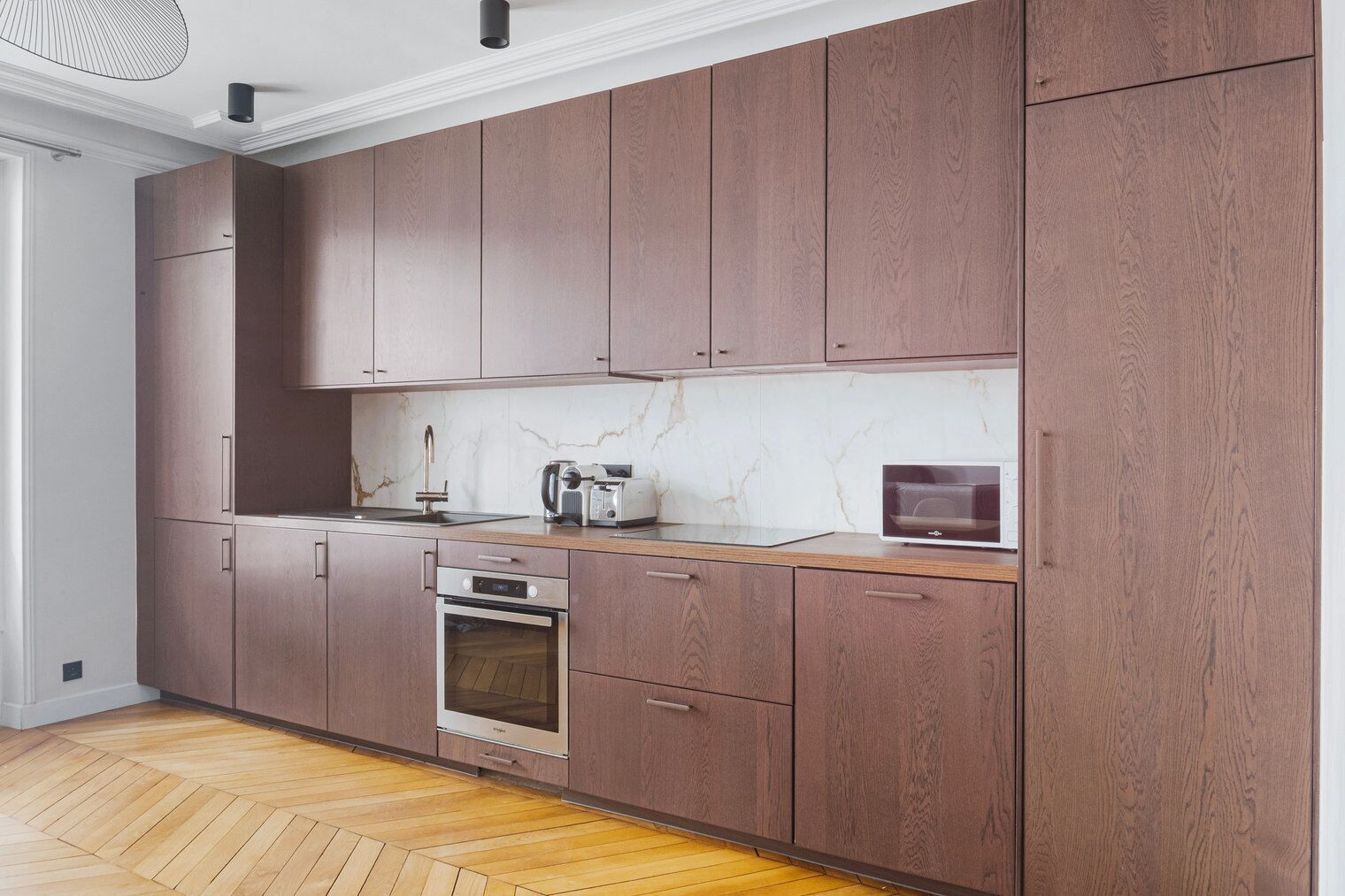 Une cuisine moderne avec des meubles en bois, un pare-feu en marbre et un four encastré.