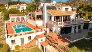 Eine große Villa mit Swimmingpool, mehreren Balkonen und Bergblick.