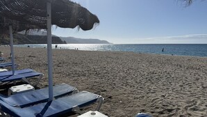 Ein Strand mit Reihen blauer Liegestühle und Reetdachschirmen.