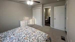 A bedroom with a bed, a ceiling fan, and two doors leading to other rooms. - Charming 3-bedroom home away from home in Rapid City! (Rapid City)