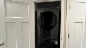 A laundry room with two stacked washers and dryers, white doors, and wooden flooring. - Charming 3-bedroom home away from home in Rapid City! (Rapid City)