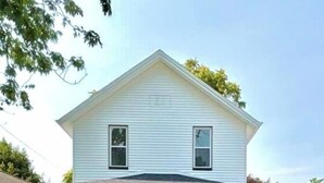 Une maison à deux étages avec un porche à l’avant, un garage et une pelouse bien entretenue.