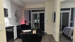 Ein modernes Wohnzimmer mit Essbereich, Küche und einem großen Fenster.