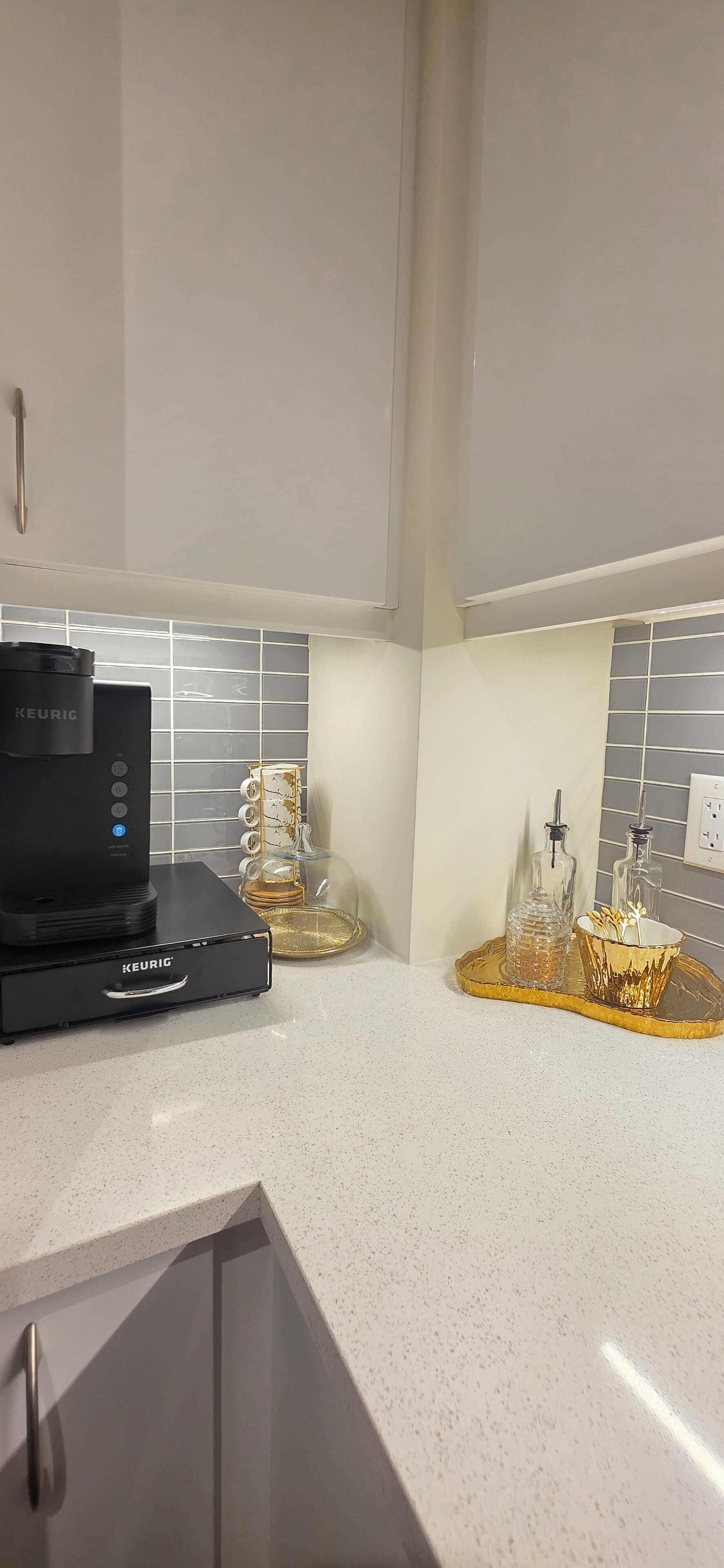 Eine Küche mit einer Keurig-Kaffeemaschine, einer Glaskaffeekanne und einem dekorativen Tablett.