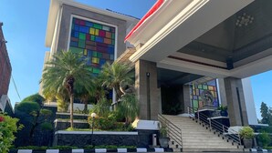 Un edificio moderno con fachada colorida, una escalera central y vegetación circundante.