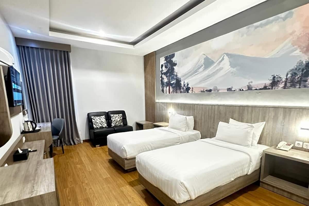 A hotel room with two beds, a desk, and a TV.