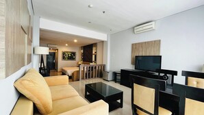 Una habitación de hotel moderna con sala de estar, cama, televisor y escritorio.