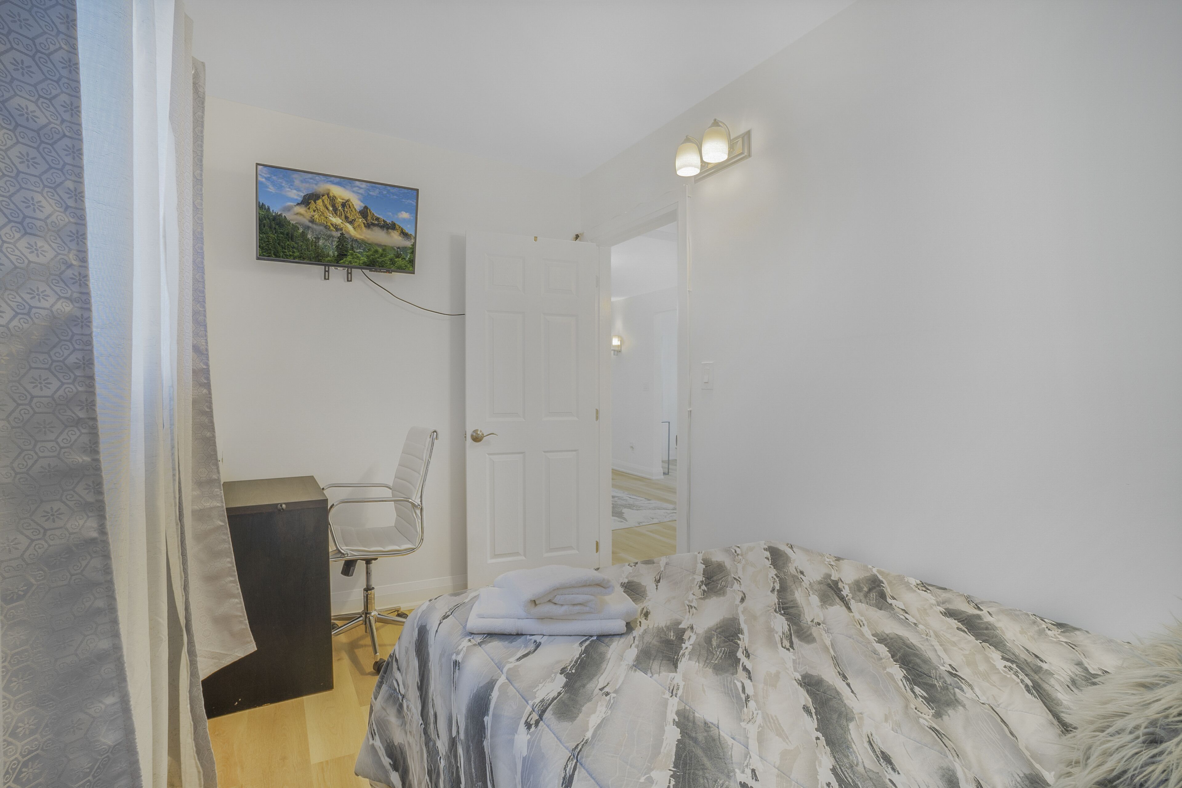 Une chambre à coucher avec un lit, une chaise, un bureau et un tableau accroché au mur.