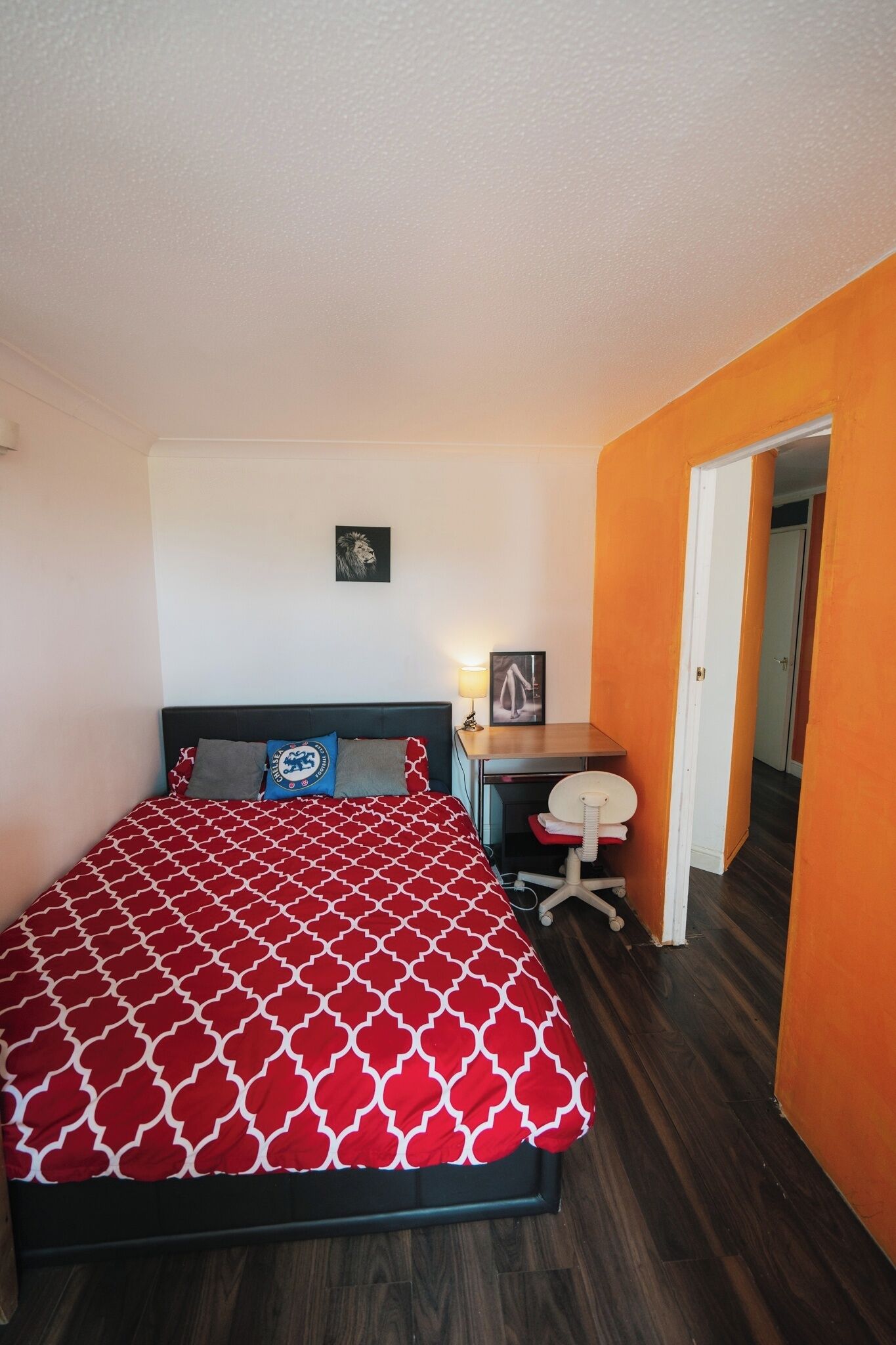 A bedroom with a bed, a desk, and a chair.