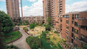 Un edificio residencial alto con varios balcones, un patio central con vegetación y una chimenea alta.