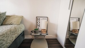 Un dormitorio con cama, una mesita con una planta, una balanza y un espejo.