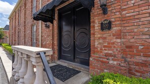 Un bâtiment en briques avec une porte noire à deux battants, une enseigne indiquant « 500 ABCD » et un petit auvent au-dessus de l’entrée.