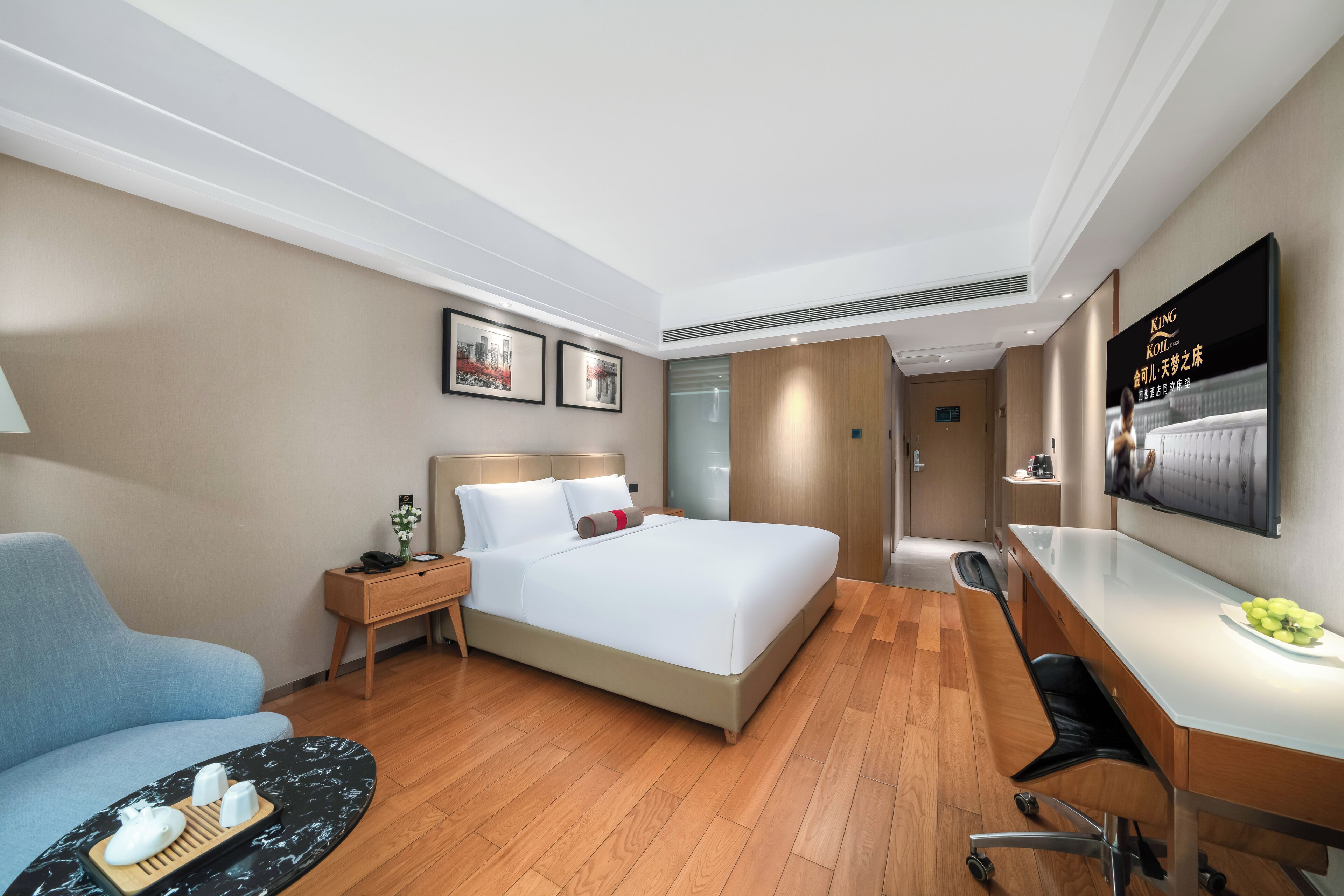 Una habitación de hotel moderna con cama, escritorio, silla, sofá y televisor.