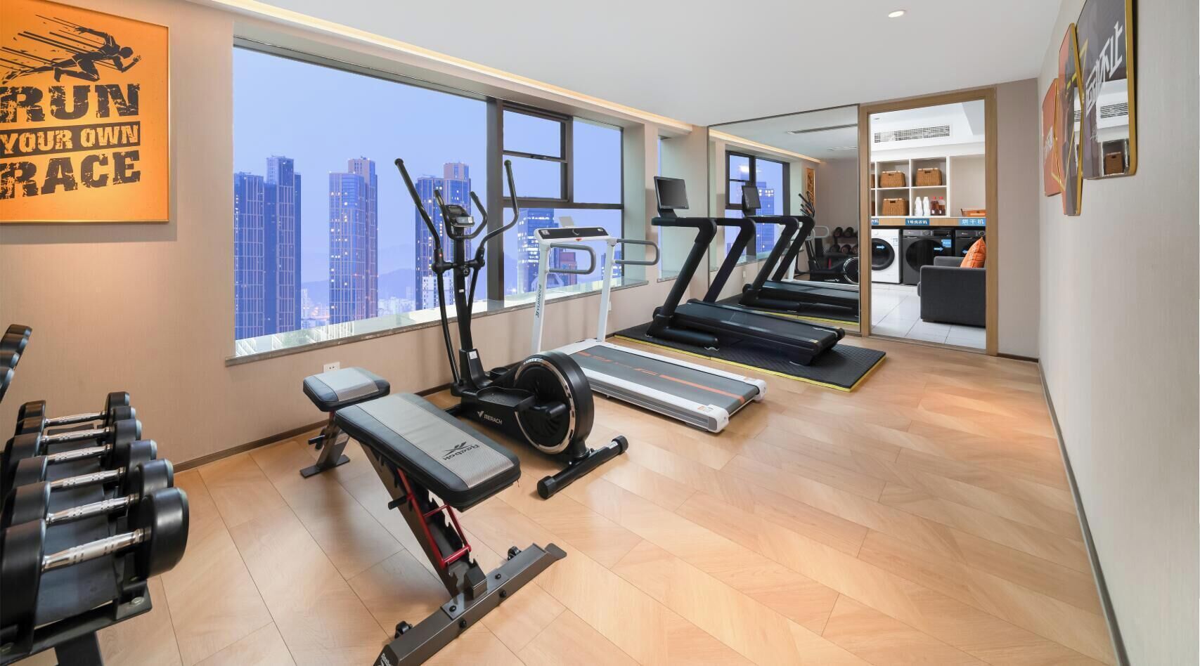 Ein Fitnessraum mit Laufbändern, einer Bank und Hanteln.
