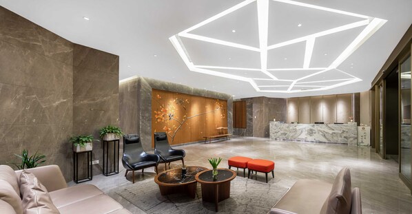 A modern lobby with a reception desk, seating area, and decorative wall.