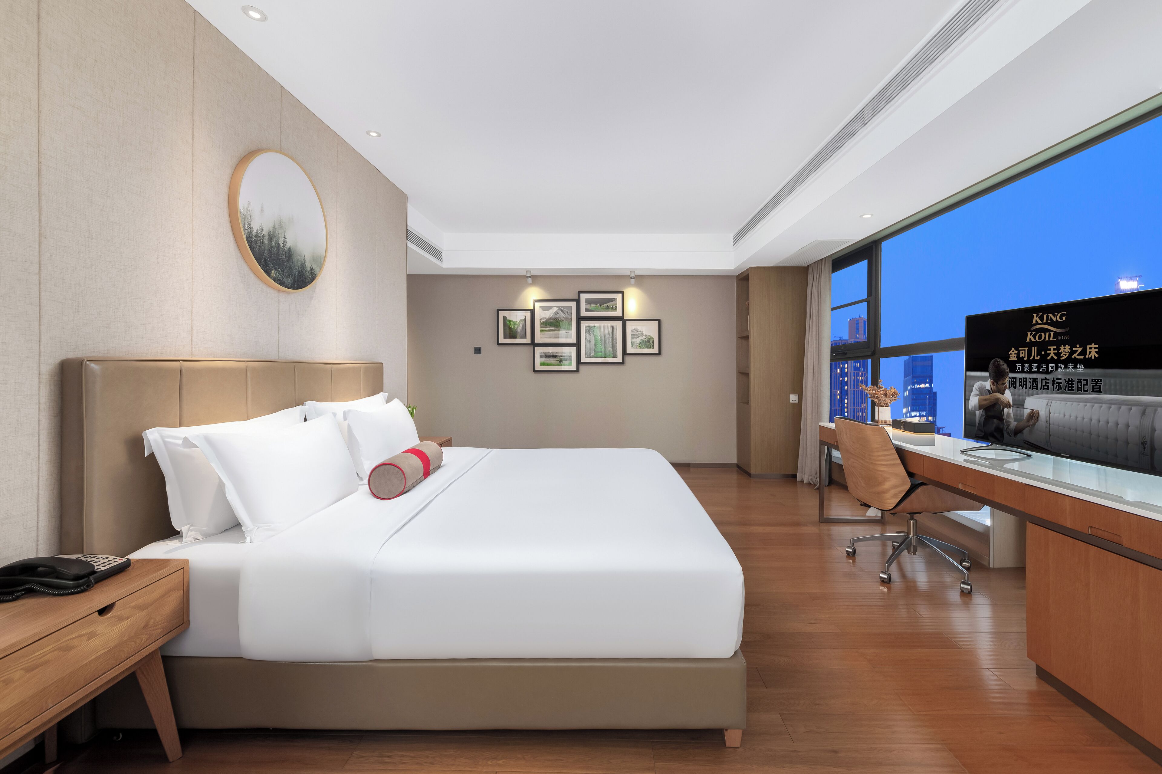 Une chambre d’hôtel moderne, dotée d’un grand lit, d’un bureau et offrant une vue sur le paysage urbain.