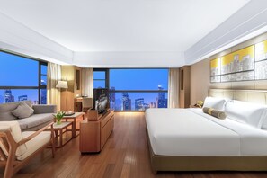 Una habitación de hotel moderna con vistas a la ciudad, una cama, un sofá, una mesa de centro y un televisor.