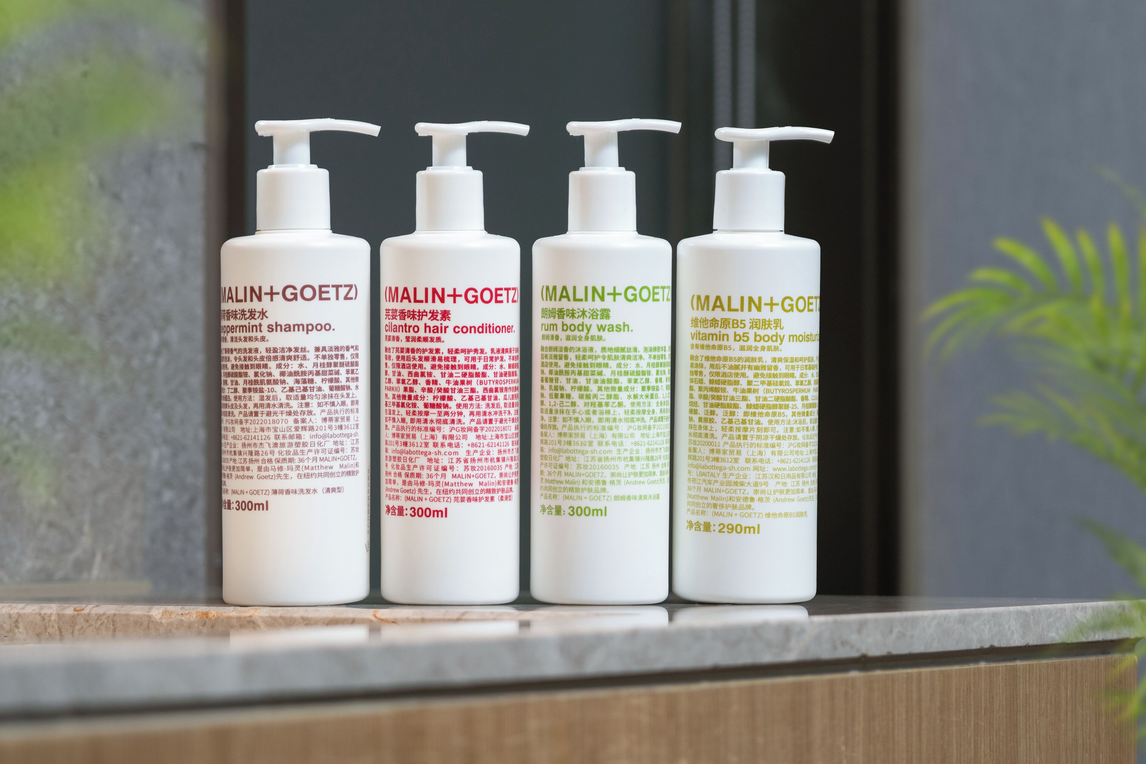 Four bottles of MALIN+GOETZ body care products on a shelf.