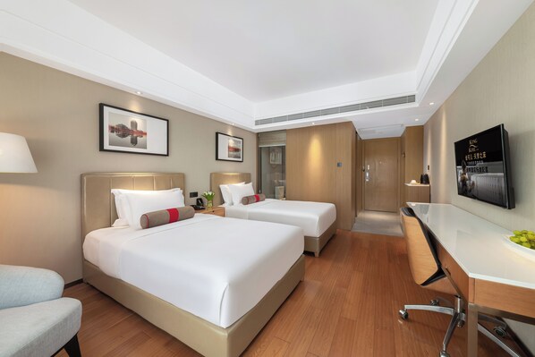 Habitación de hotel con dos camas, un escritorio y un televisor.