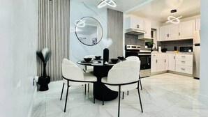 Una cocina moderna con armarios blancos, encimera negra y un comedor con mesa redonda y sillas.