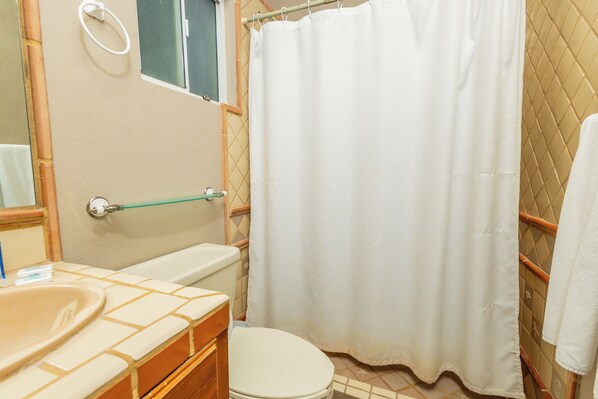 Un baño con inodoro, lavamanos y cortina de ducha.
