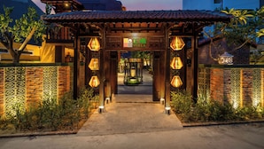A traditional-style entrance with a wooden archway, illuminated by hanging lanterns, leading to a pathway. - DEMIN VILLA HOI AN - Pool and BBQ Garden (Thanh pho Hoi An)