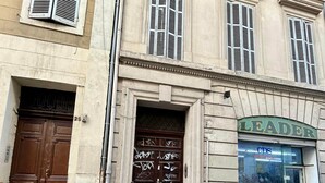 A building with a large wooden door, a smaller door with graffiti, and a storefront with the name "LEADER" above it.