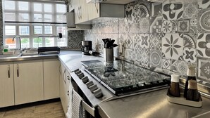 A modern kitchen with a stainless steel stove, a coffee maker, and patterned backsplash tiles.
