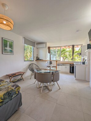 A modern kitchen with a dining area, a small table with a chair, and a sofa.