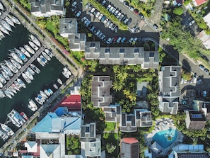 An aerial view of a marina with boats docked, a swimming pool, and modern buildings with balconies. - Studio Zaboka - Beaches & Marina Ideal for couples, many activities on foot! (Les Trois-Îlets)