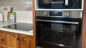 Une cuisine avec des meubles de rangement en bois, un four à micro-ondes, un four traditionnel et un grille-pain.