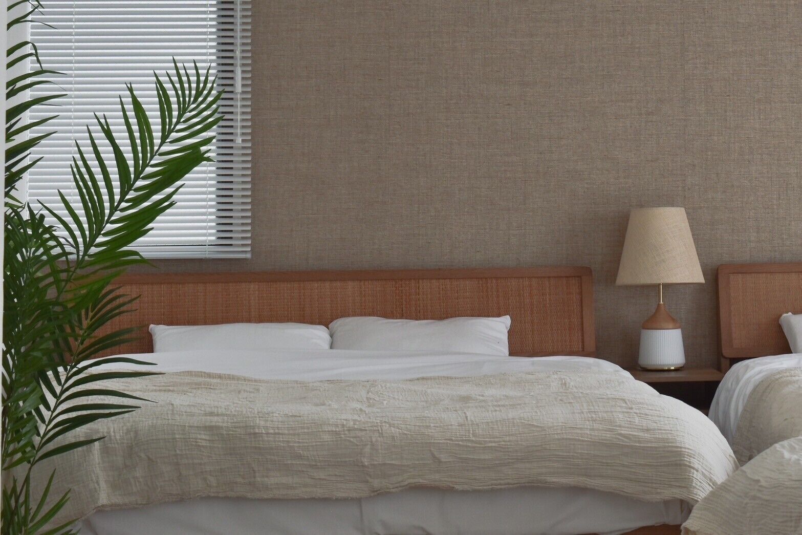 Une chambre d’hôtel avec un grand lit, une tête de lit en bois, une lampe de chevet et une plante.