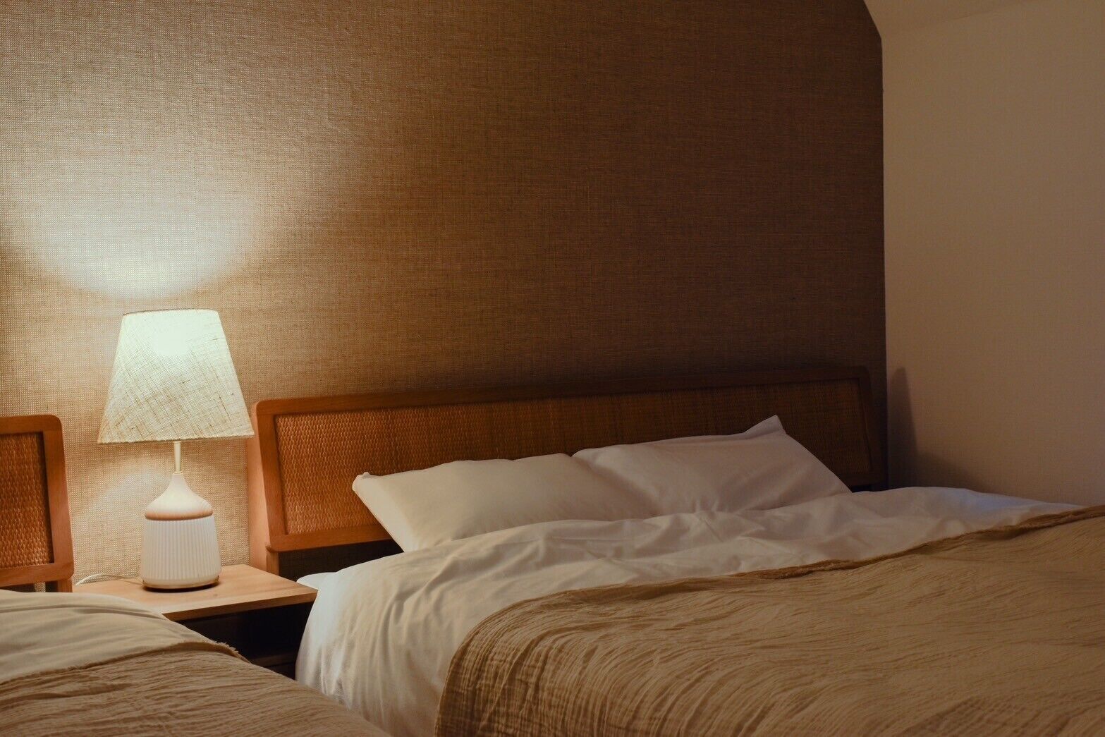 Une chambre d’hôtel avec un grand lit, une table de chevet avec une lampe et une tête de lit.