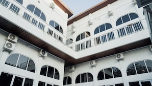 A multi-story building with balconies, large windows, and air conditioning units. - Escotel Melasti (Ungasan)
