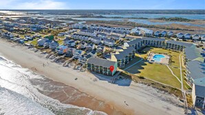 An aerial view of a coastal residential area with houses, a beach, and a large body of water in the background. - The Endless Wave: Oceanfront Condo, Sunrise View, Pool, 1-mile to Dining & Pier (Surf City)