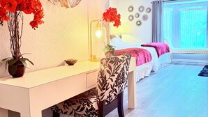 Un dormitorio moderno con una cama blanca, un escritorio con silla, un ventanal grande y un ventilador de techo.