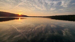 Ein ruhiger See bei Sonnenuntergang mit klarem Himmel und fernen Bergen.